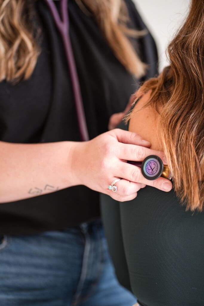 Branding photo of a provider's hands using a stethoscope during a client assessment, highlighting detailed patient care.