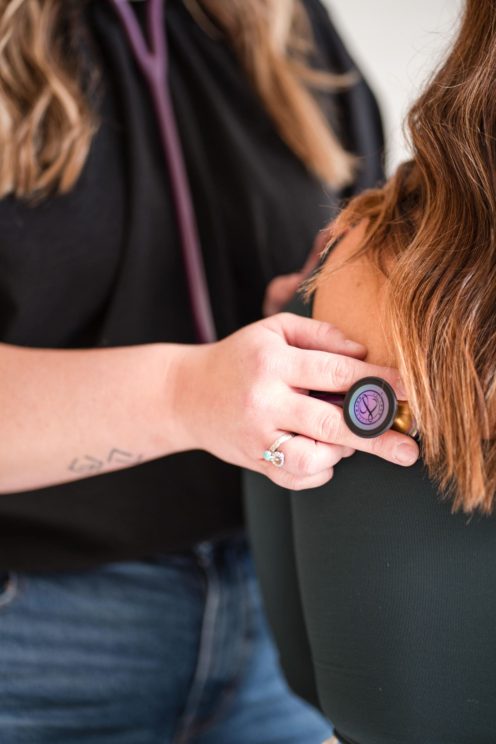 Branding photo of a provider's hands using a stethoscope during a client assessment, highlighting detailed patient care.