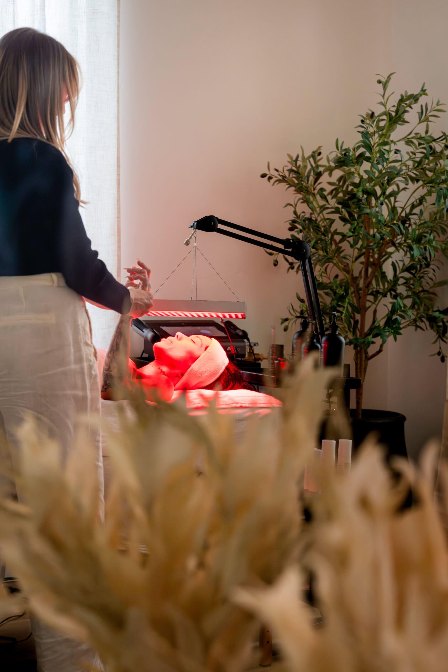 aesthetician providing red-light therapy to client in treatment room