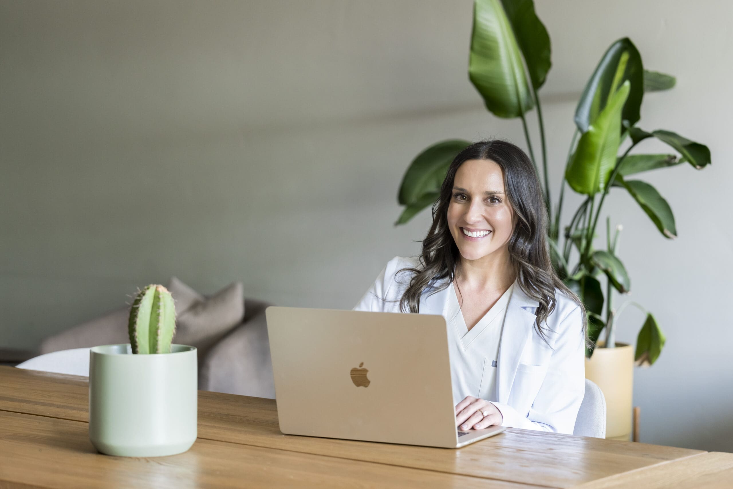 Lifestyle branding photo of skincare provider with products and laptop in wellness office