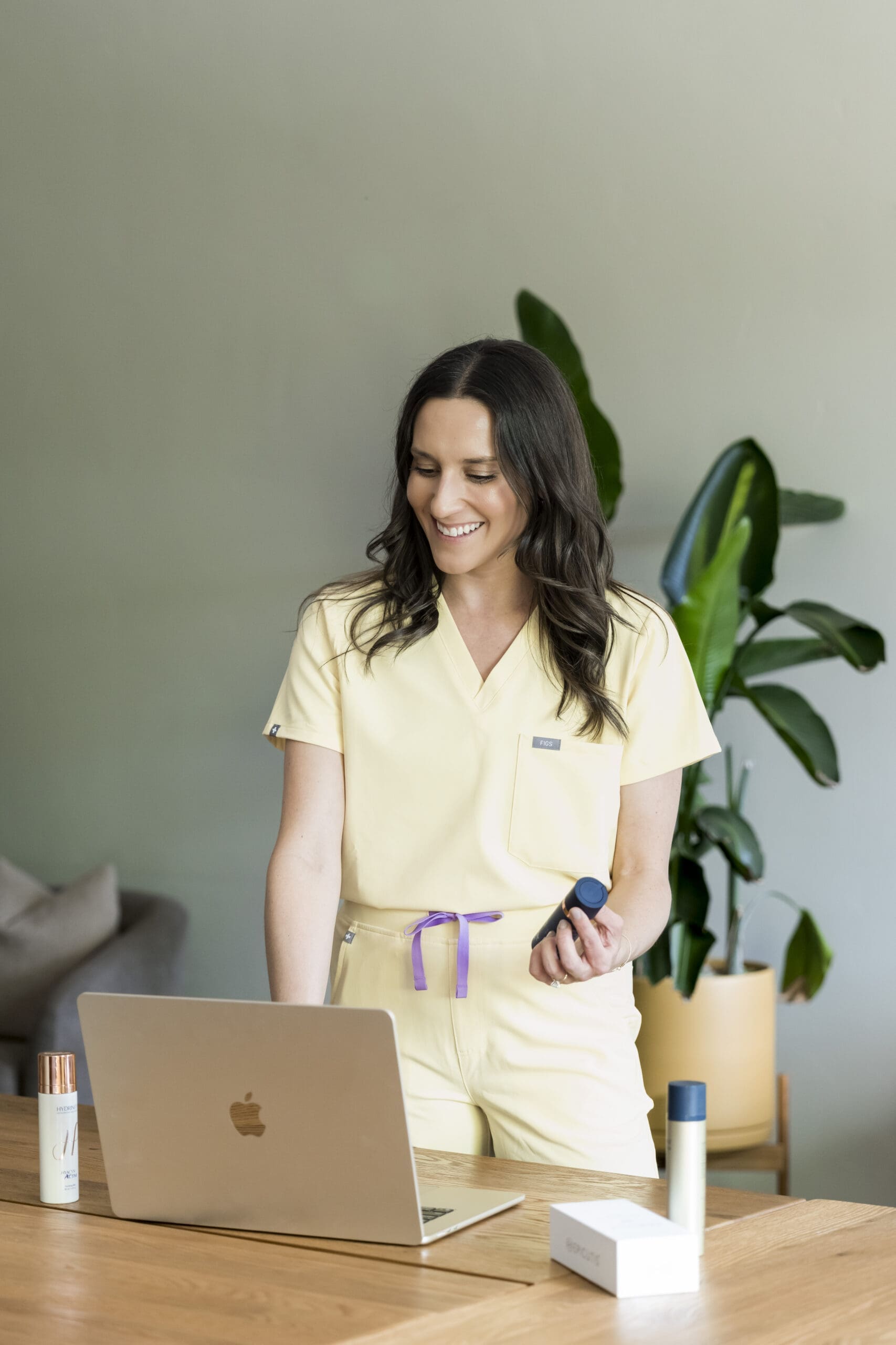 Lifestyle branding photo of skincare provider with products and laptop in wellness office