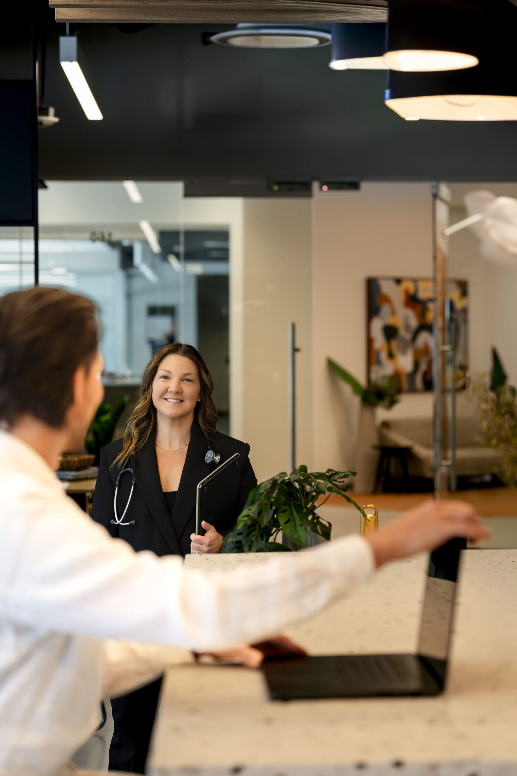 Lyndsy greeting a concierge medicine client in a modern executive office during a Boise branding photography session.