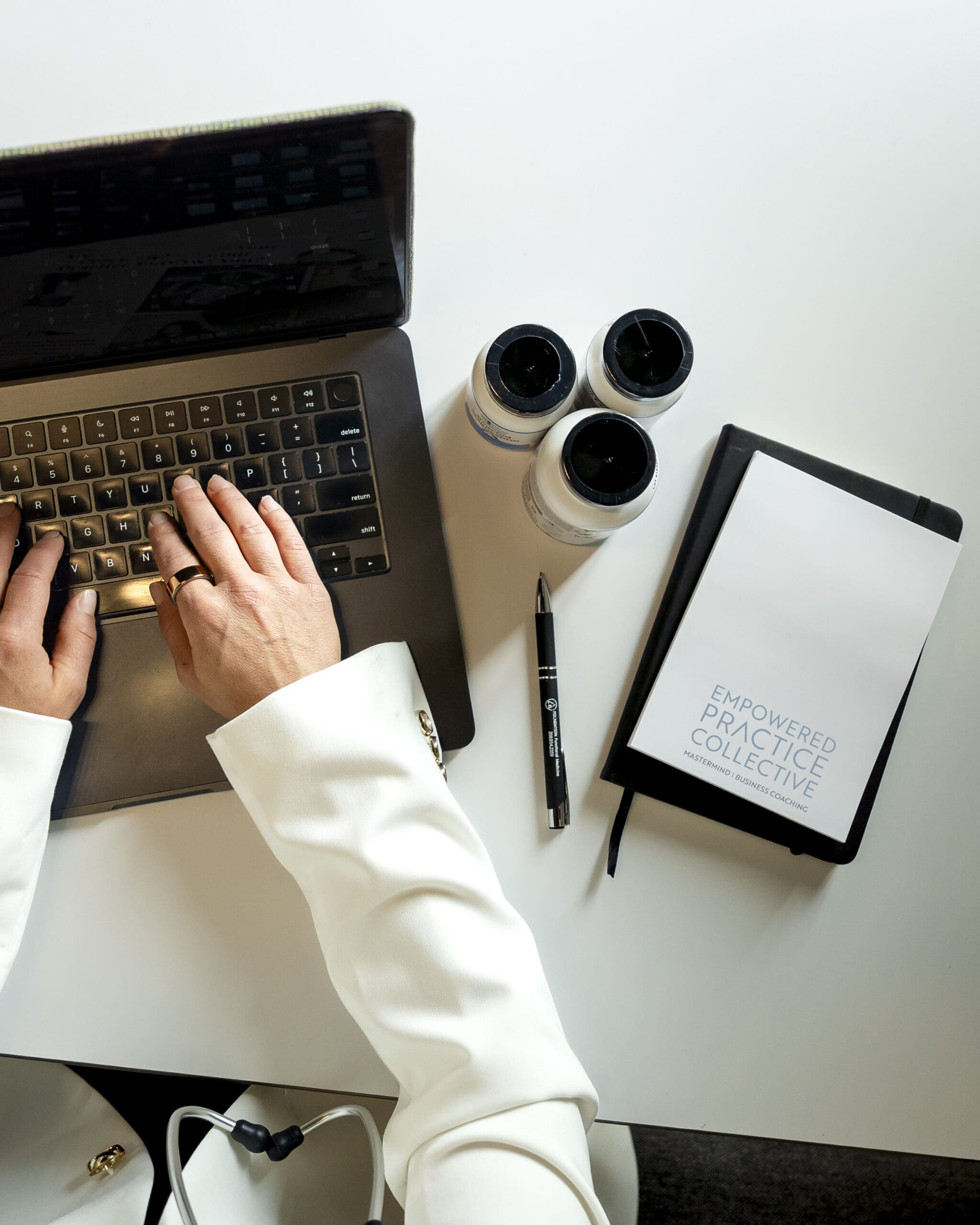 Workspace details featuring a laptop, wellness supplements, and business coaching notebook during a branding session.