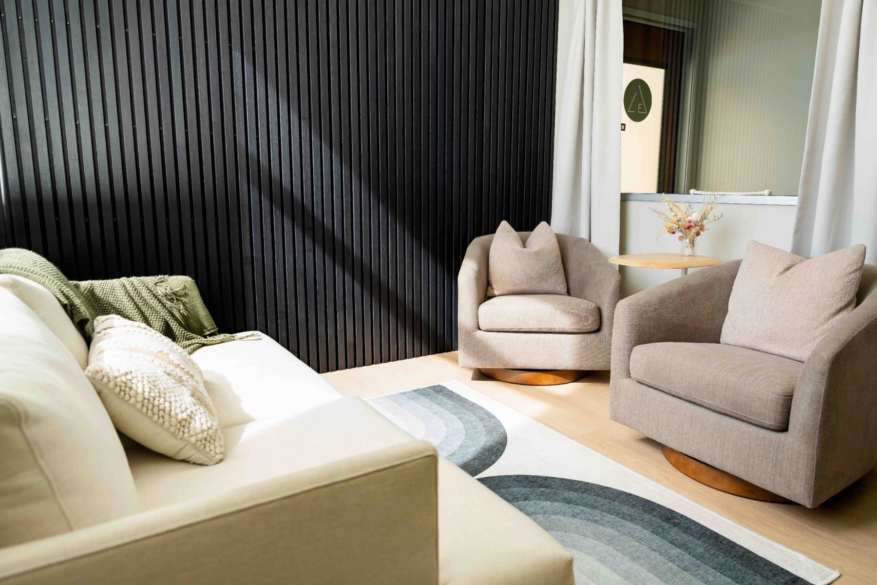 Cream sofa and neutral armchairs beside a black textured wall