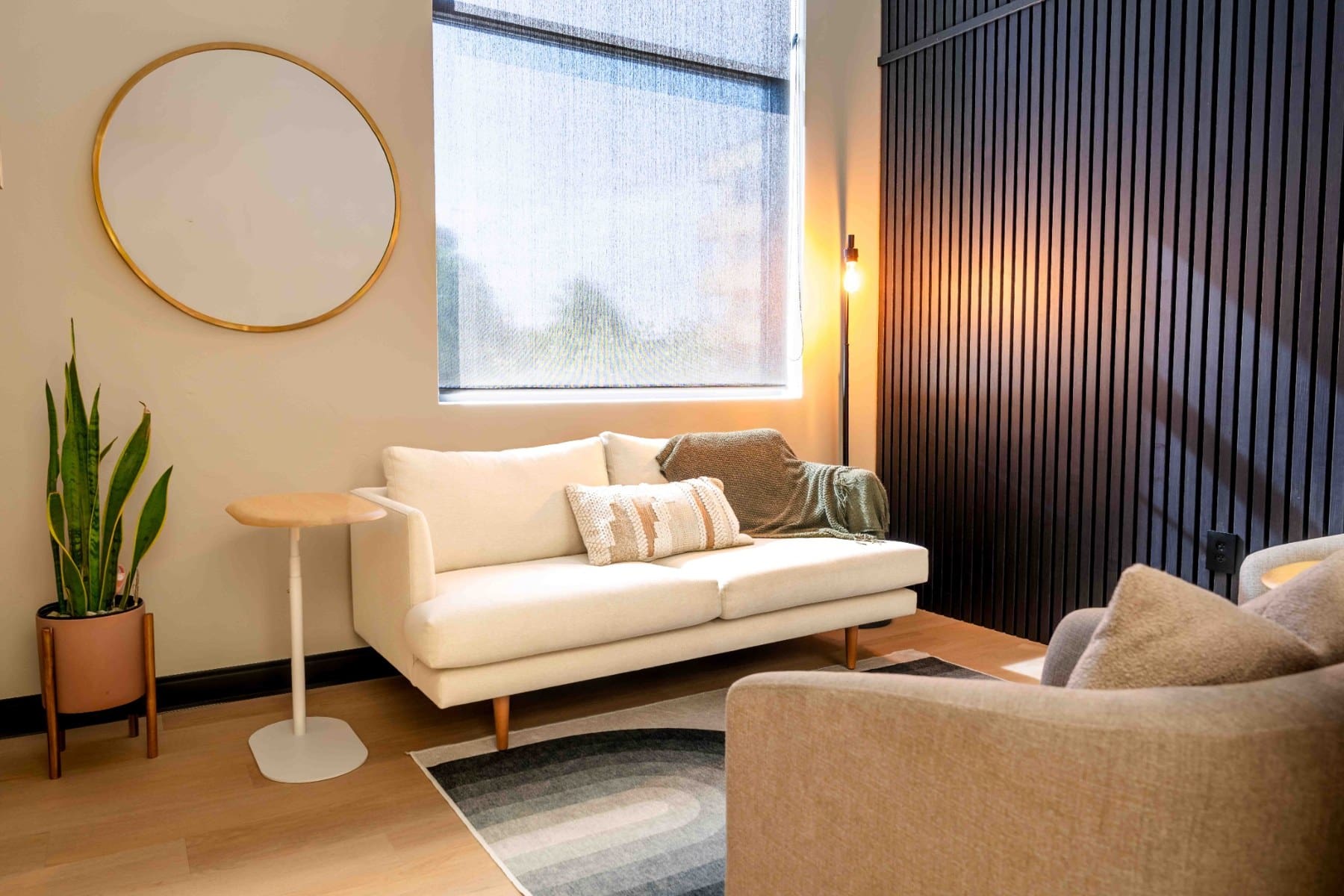 Sunlight falling across a cream sofa beneath a round wall mirror